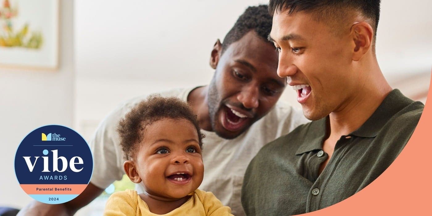 A couple smiling admiringly while holding a baby